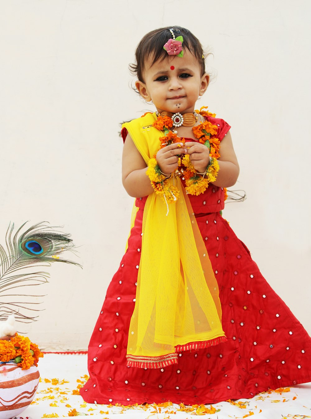 muchacha en vestido rojo y amarillo sosteniendo ramo de flores amarillas