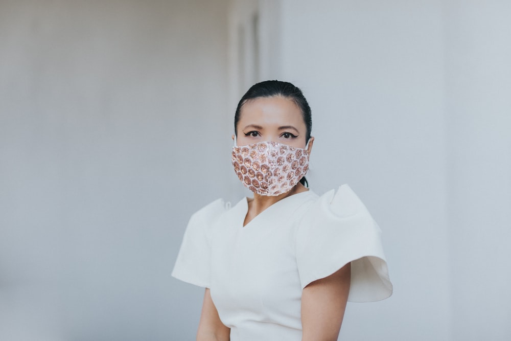 woman in white shirt covering her face with white and red face mask