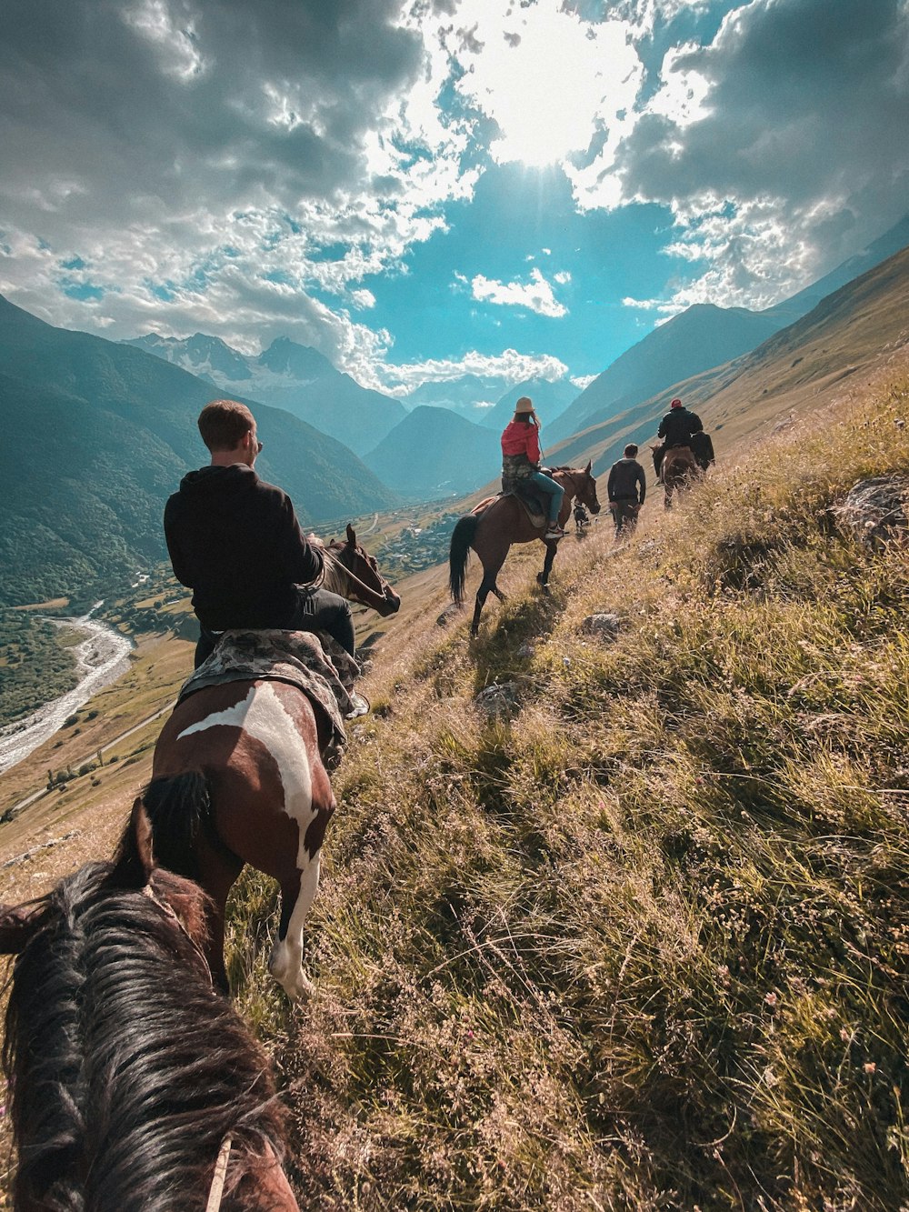 people riding horses on green grass field during daytime