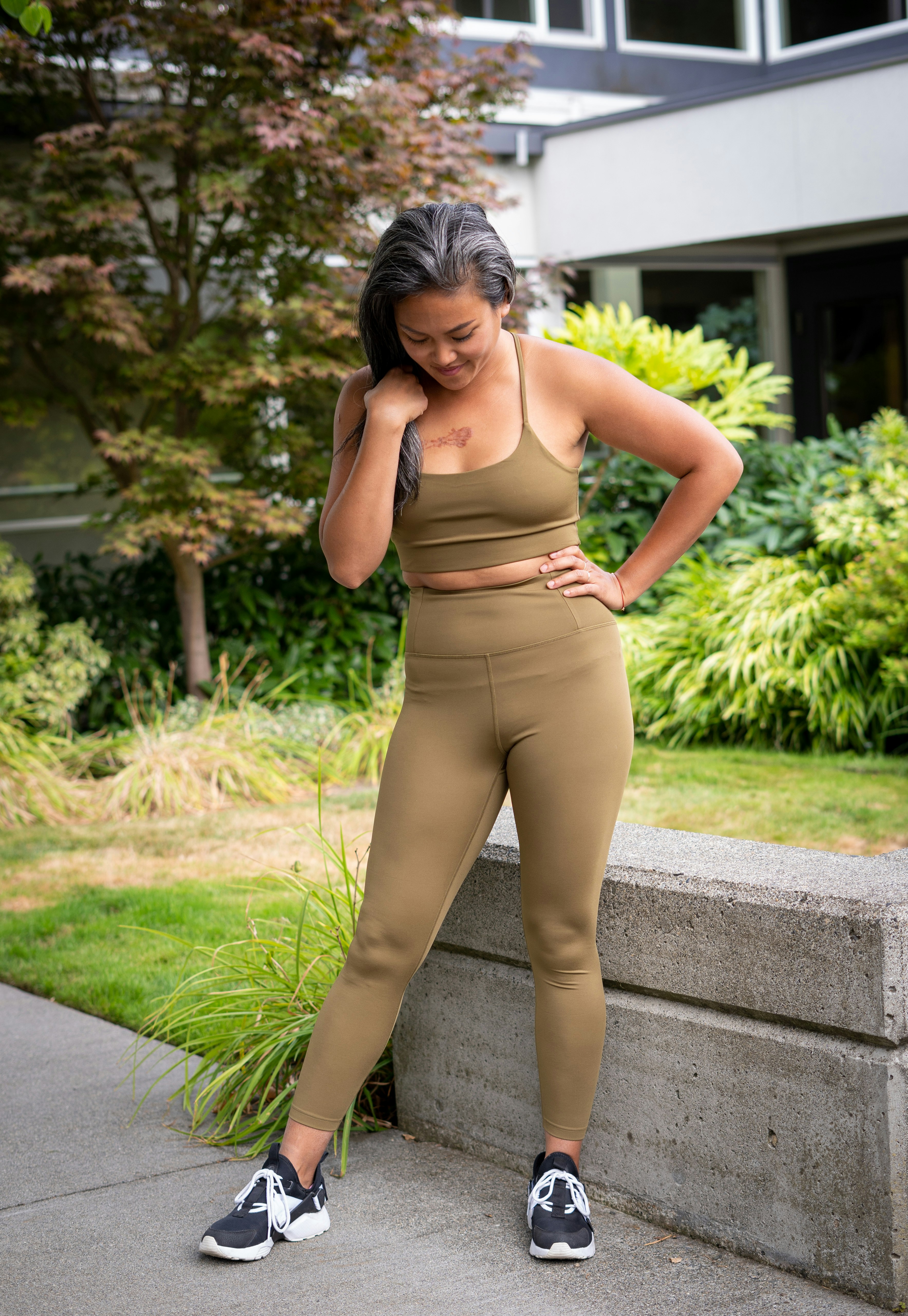 woman in brown bra and brown pants standing on gray concrete pathway during daytime