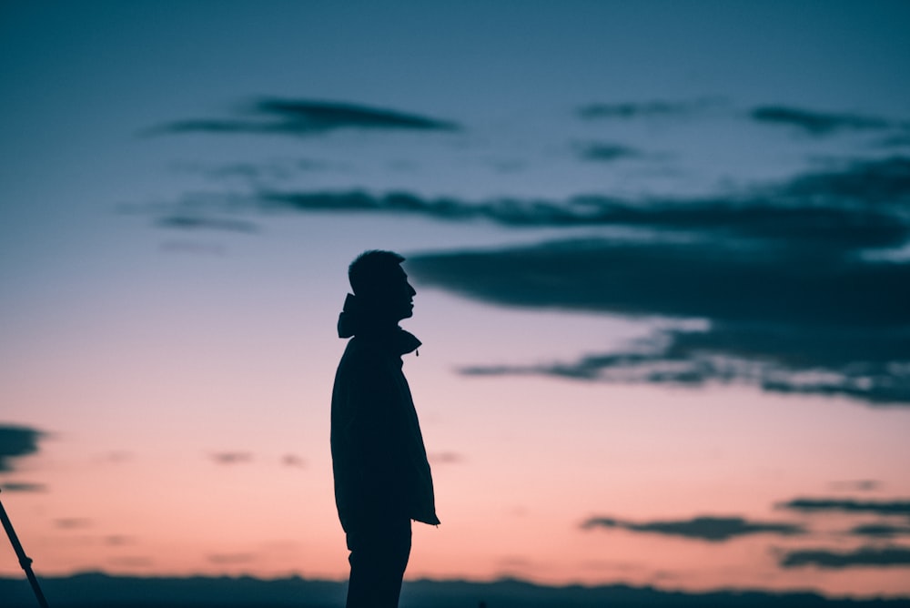 silhouette of man standing under cloudy sky during daytime