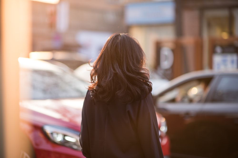 woman in black coat standing near cars during daytime
