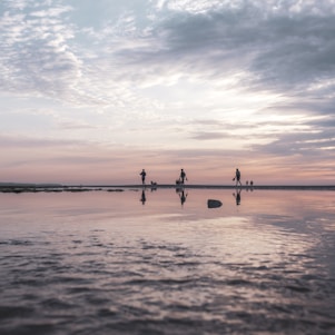 A serene sunset beach walk with a small group sharing smiles and laughter along the shore.