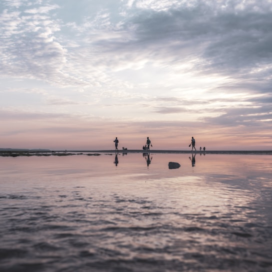 A serene sunset beach walk with a small group sharing smiles and laughter along the shore.