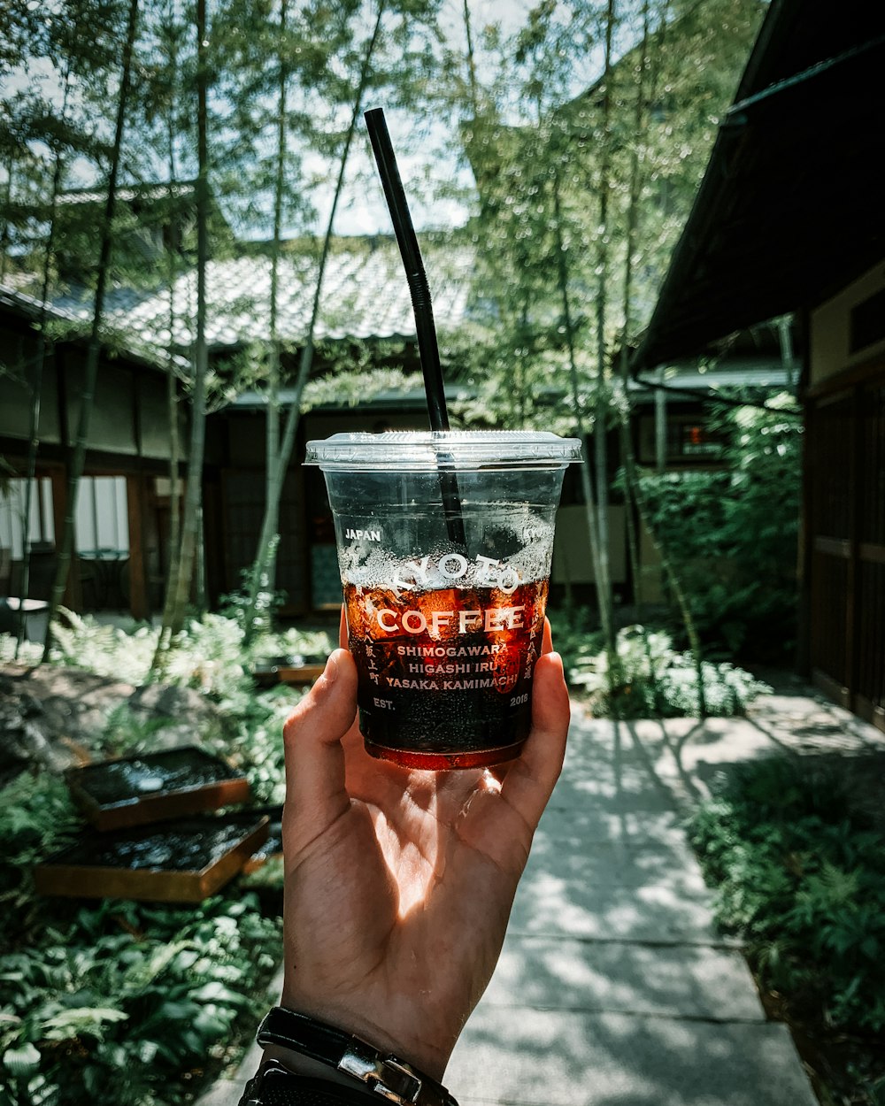 person holding clear plastic cup with red liquid