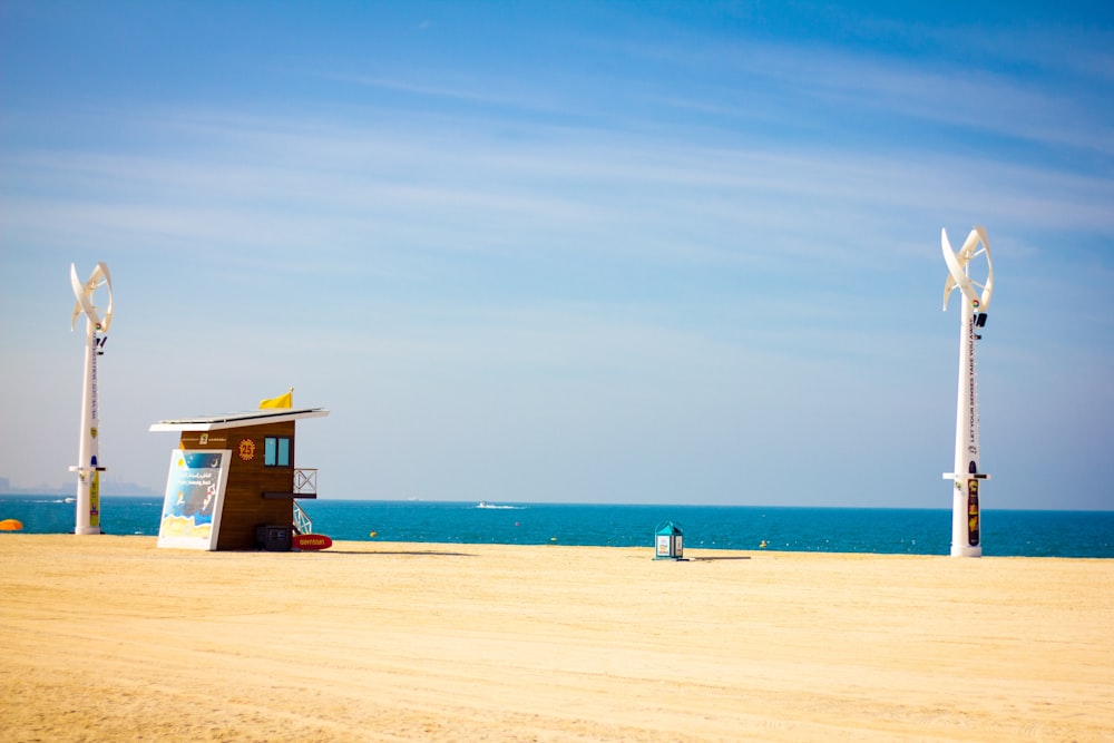 Casita de salvavidas de madera marrón en la orilla de la playa durante el día