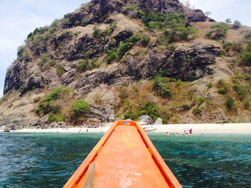 orange kayak on body of water near mountain during daytime