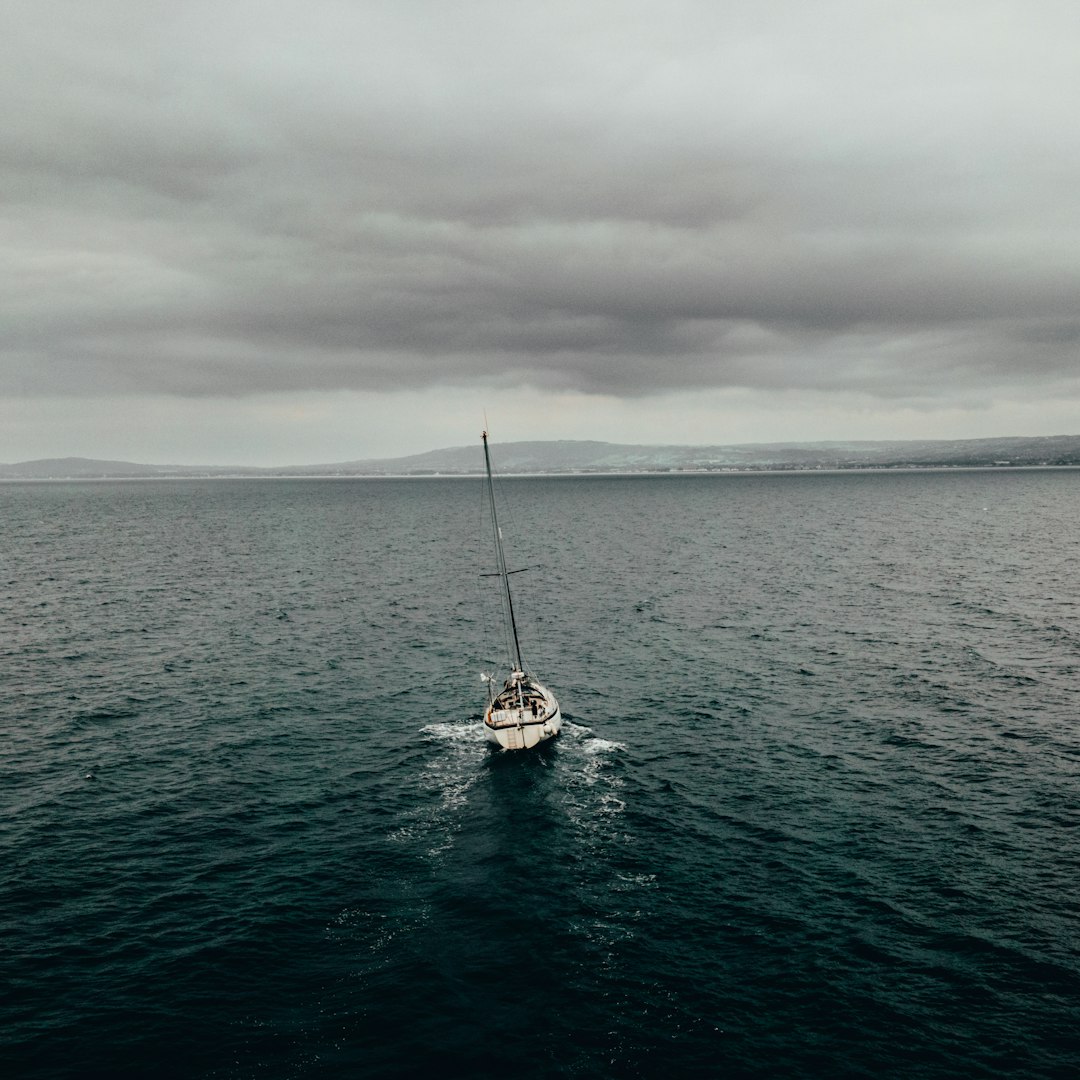 white sailboat on sea under gray sky