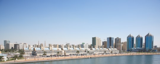 city buildings near body of water during daytime in Sharjah - United Arab Emirates United Arab Emirates