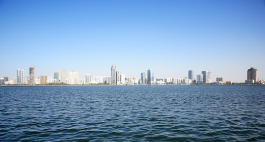 city skyline across body of water during daytime in Sharjah - United Arab Emirates United Arab Emirates