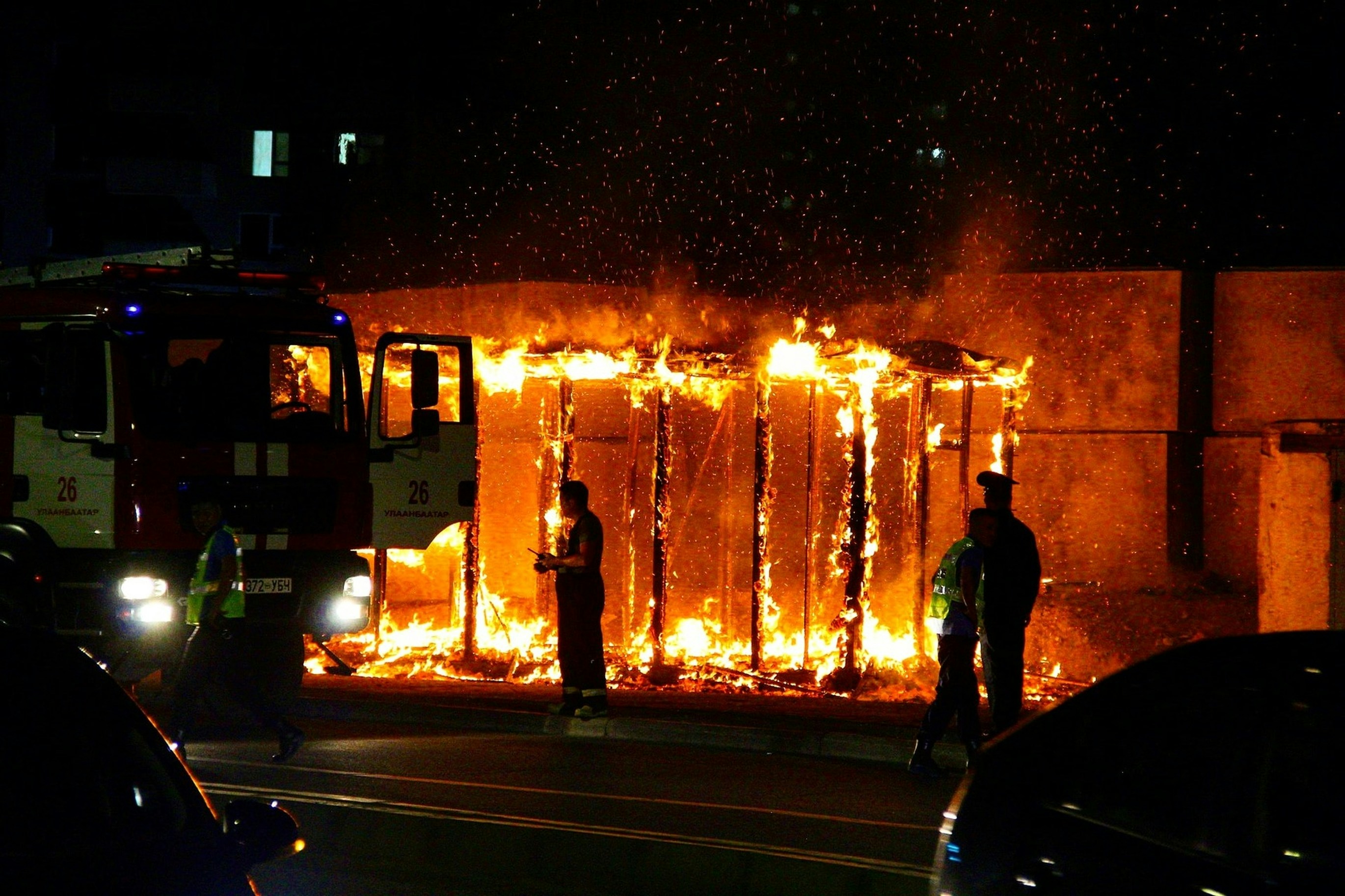 man in black jacket standing near fire during night time