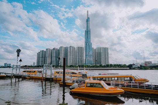 white and brown boat on water near city buildings during daytime in District 2 Vietnam