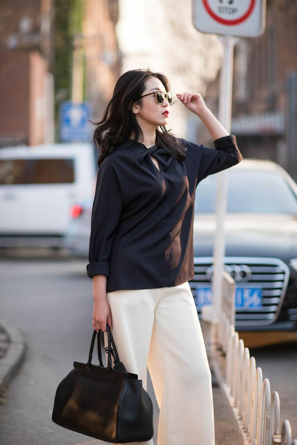 woman in black long sleeve shirt and white pants wearing sunglasses