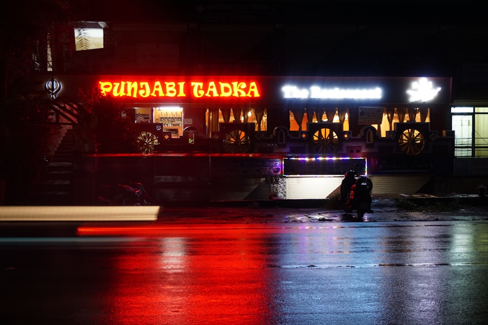 man in black jacket sitting on bench in front of store during night time