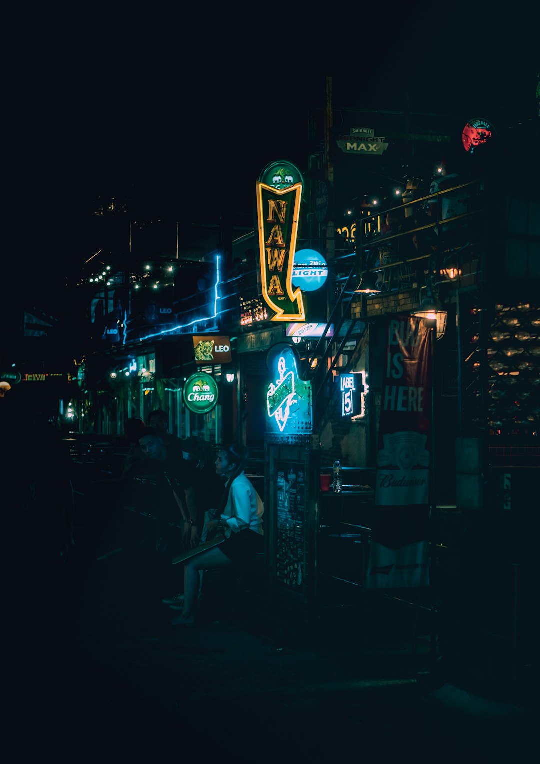 man in black jacket standing near blue and red neon signage during nighttime