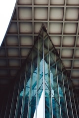 Geometric glass and metal structures with reflections create an abstract architectural pattern. The use of lines, grids, and angles highlights modern design, with a harmonious blend of symmetry and structure.