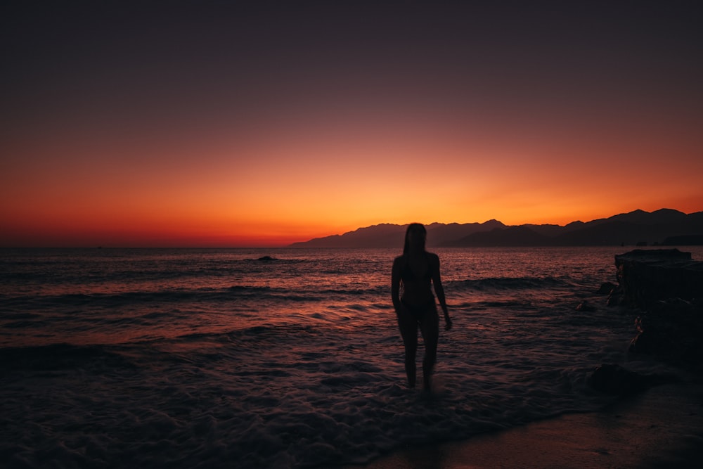 Silhouette von Mann und Frau, die bei Sonnenuntergang am Strand stehen