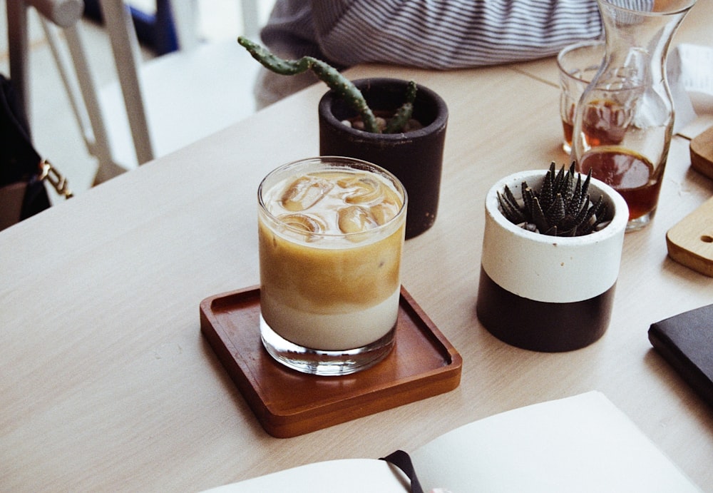 clear drinking glass with brown liquid on brown wooden tray