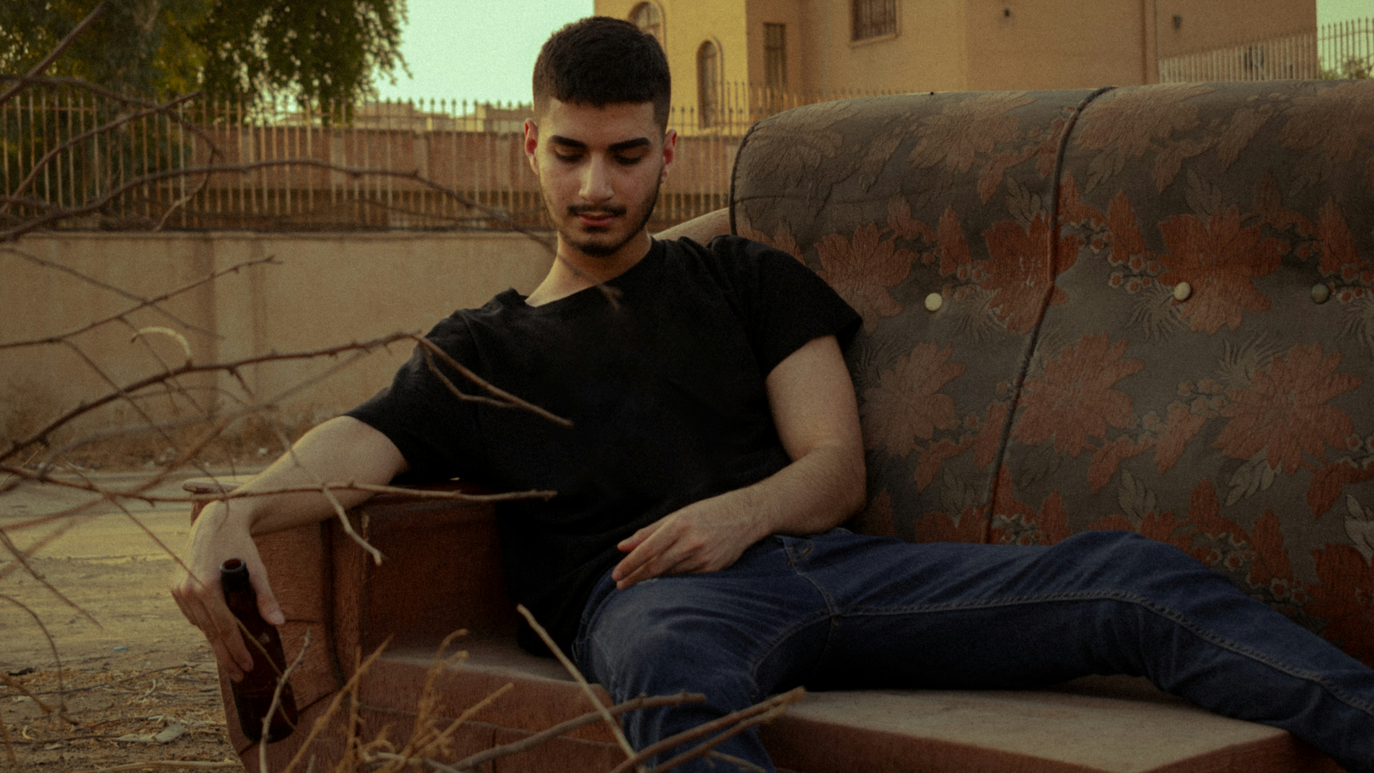 man in black crew neck t-shirt and blue denim jeans sitting on brown sofa