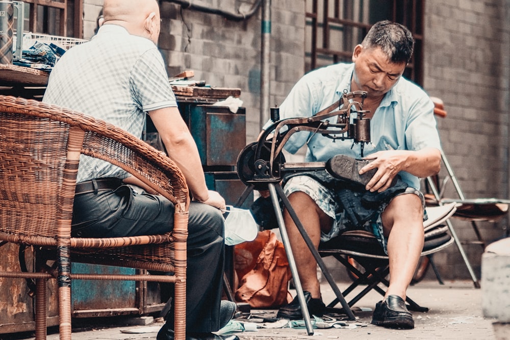 man in white and black checkered button up shirt sitting on brown wooden armchair