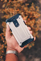 Hands holding a smartphone protected by a rugged Duraviva cover.