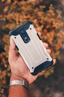 Lifestyle shot of a person holding an iPhone with the Voltek case outdoors, illustrating durability in action.