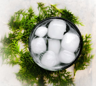 Top-down view of crushed ice being carefully packed into a medium-sized saunapearls mold on a white background