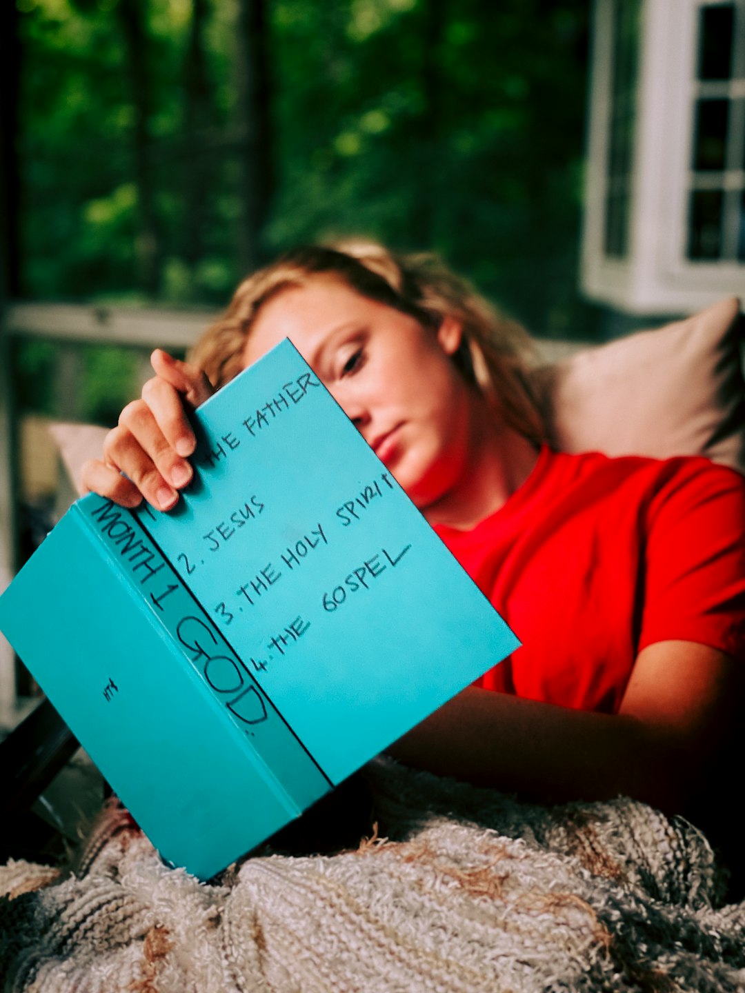 woman in red shirt holding blue book