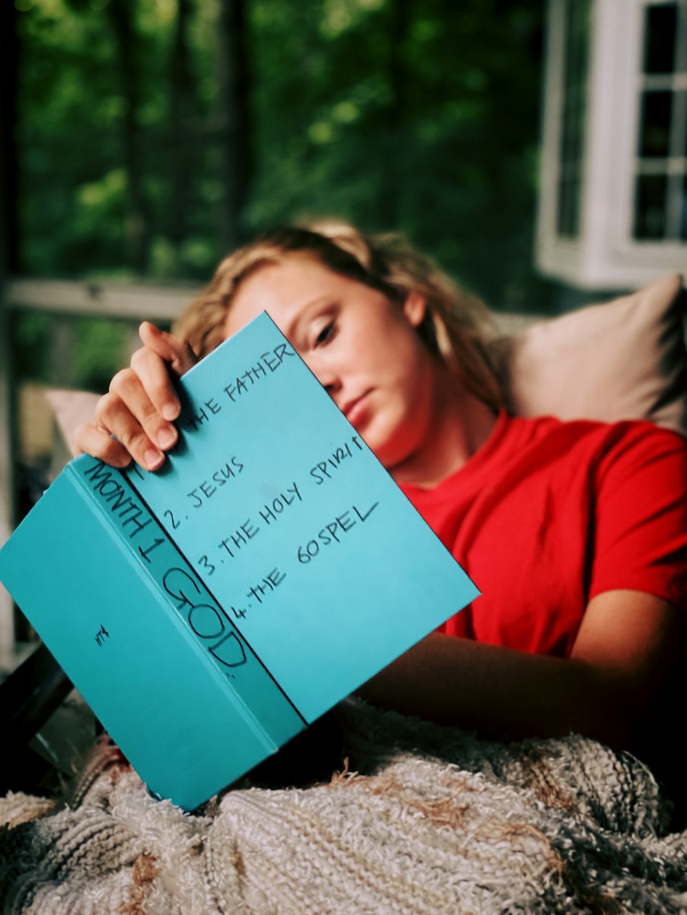 woman in red shirt holding blue book