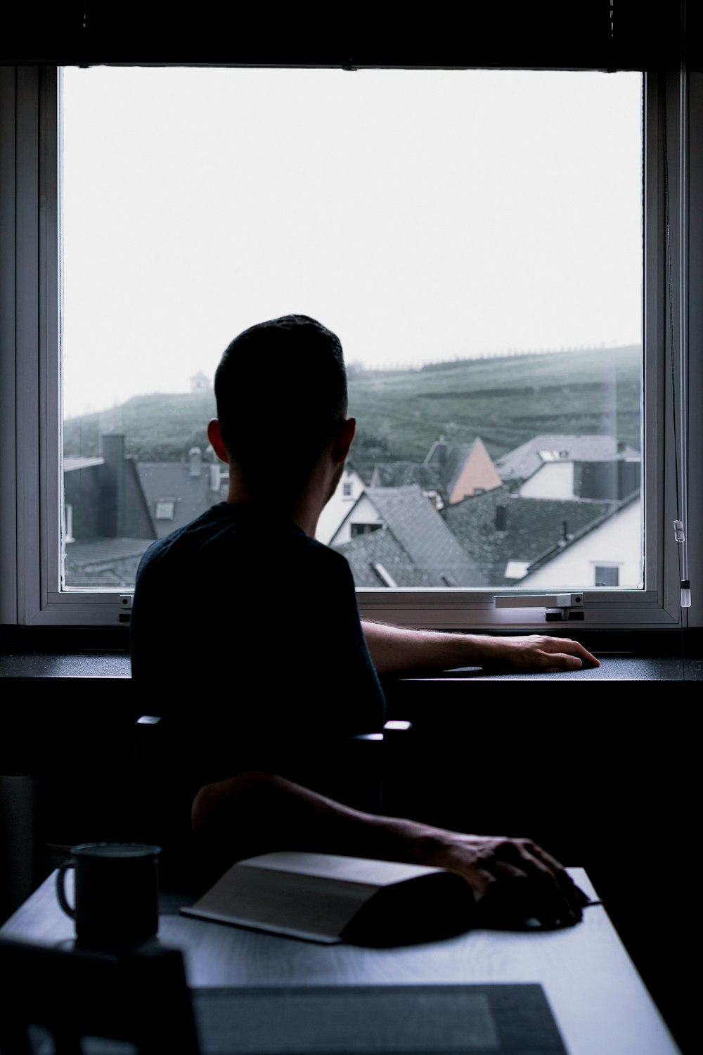 man in black shirt sitting by the window