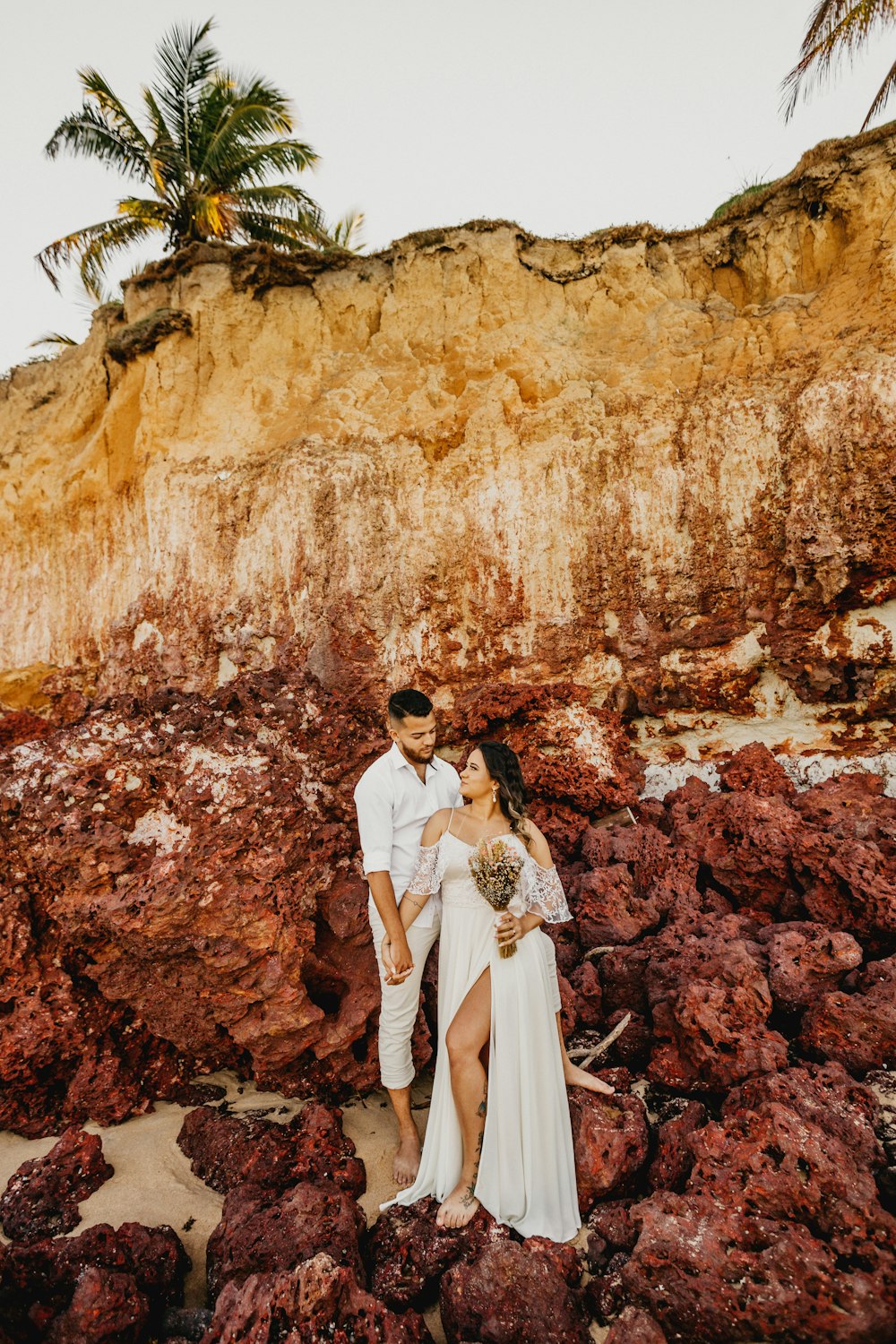 man and woman in white wedding dress standing in front of brown rock formation during daytime