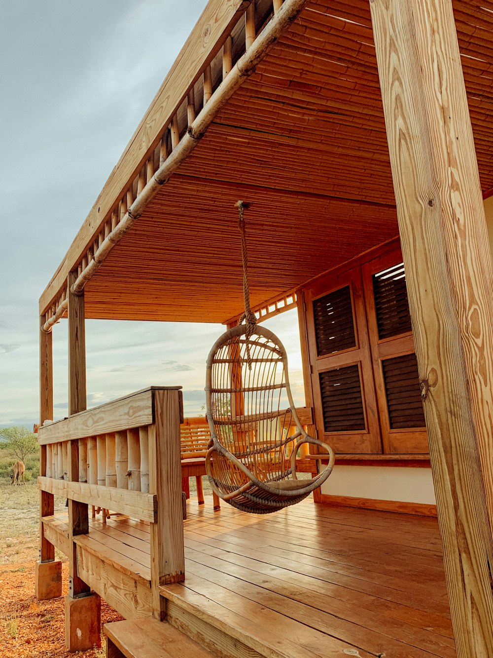a wooden porch with a hanging chair on it