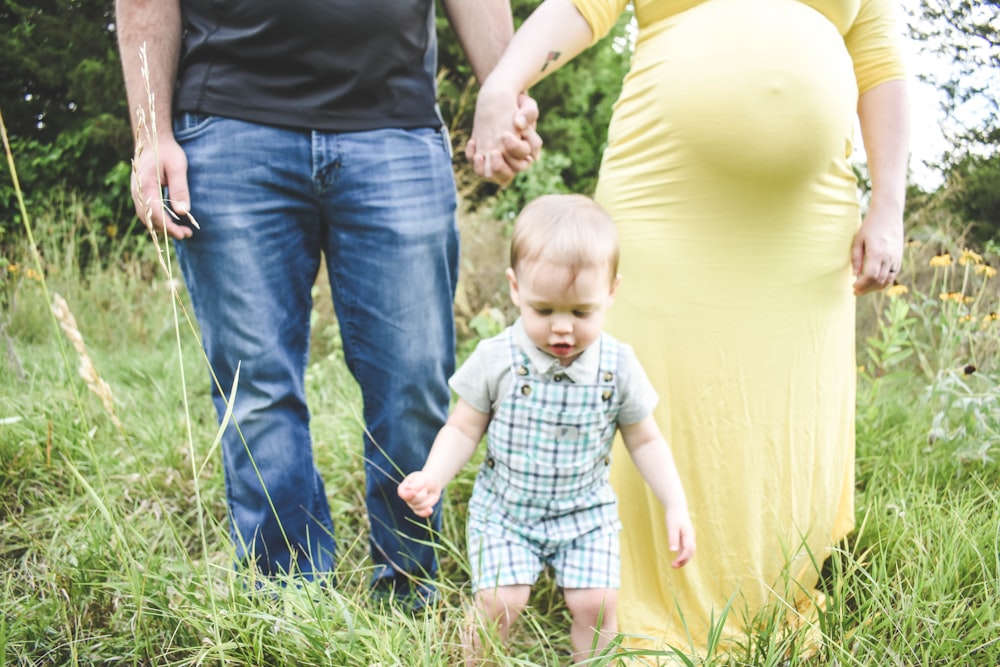 man in black tank top carrying baby in blue and white plaid button up shirt