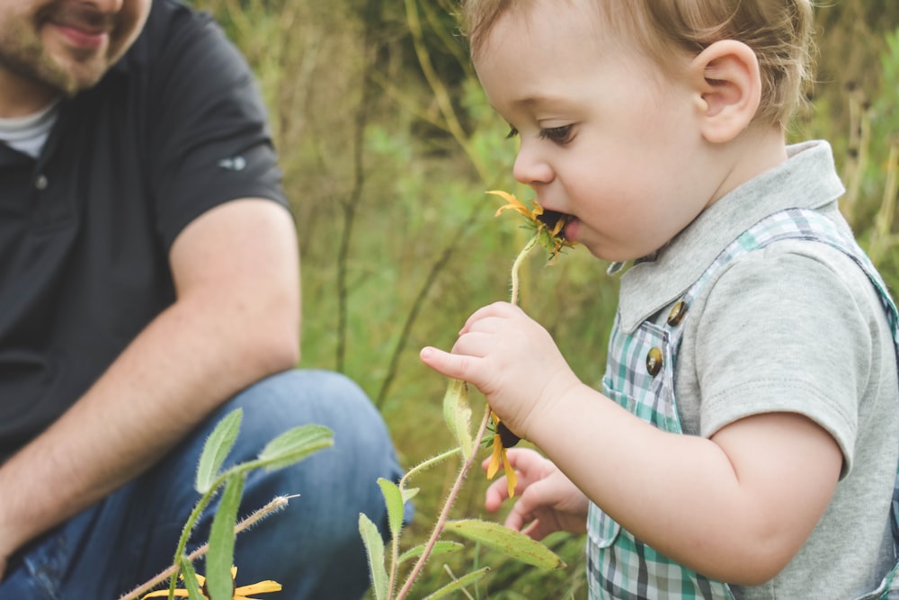 boy in blue polo shirt holding green plant