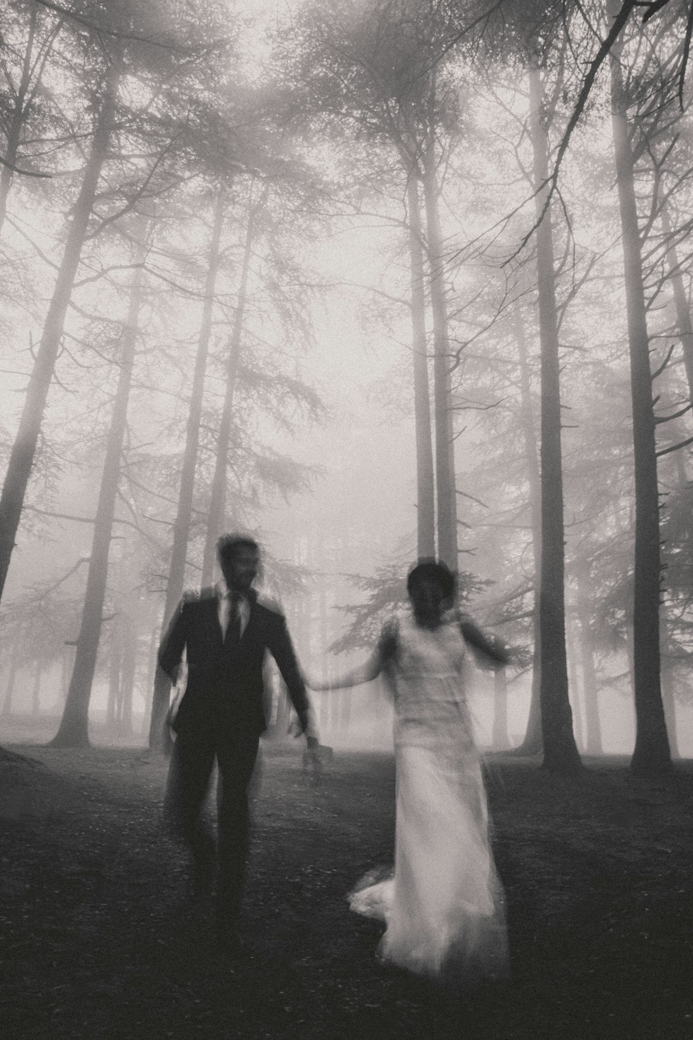 grayscale photo of man and woman walking on forest