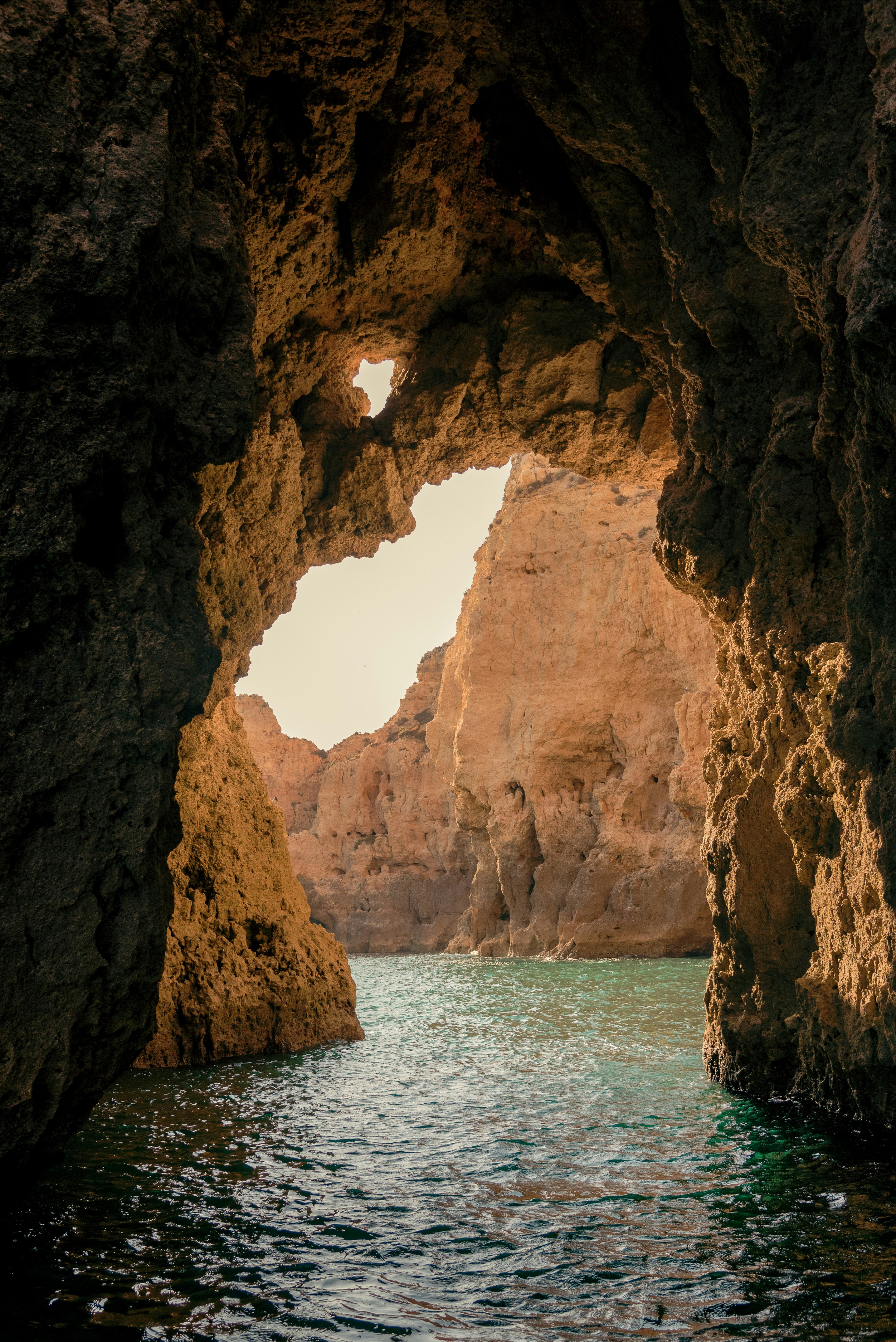 brown cave on blue sea water during daytime