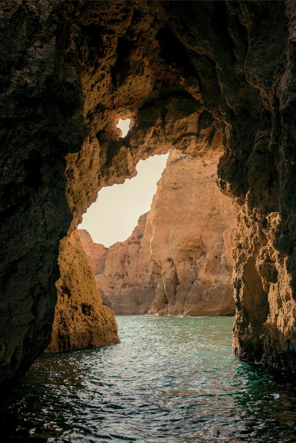 brown cave on blue sea water during daytime