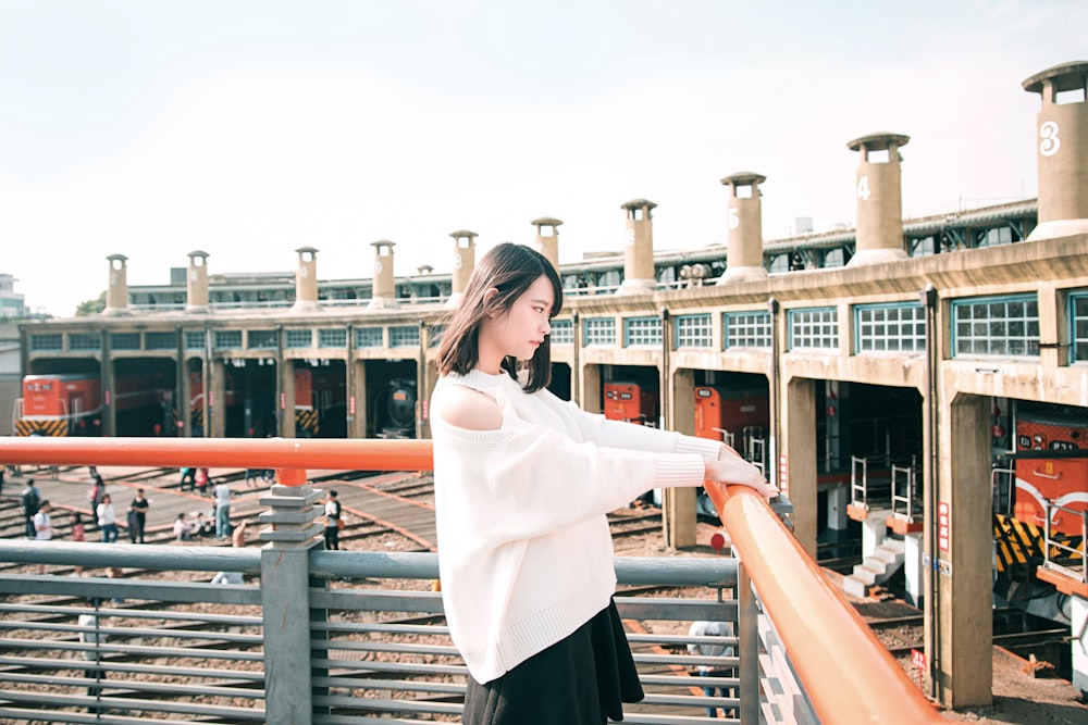 woman in white long sleeve shirt and black skirt standing on brown wooden bridge during daytime