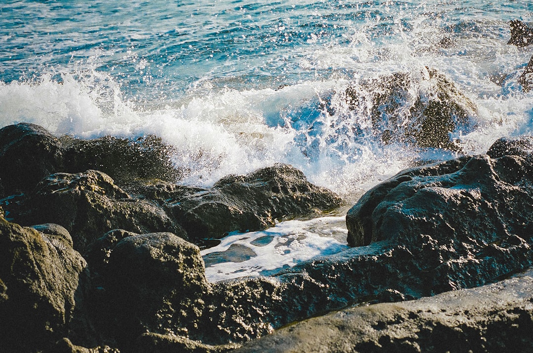 ocean waves crashing on black rock formation during daytime