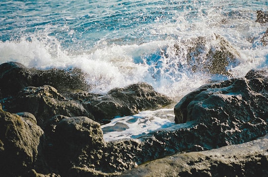 ocean waves crashing on black rock formation during daytime in Isshiki Japan