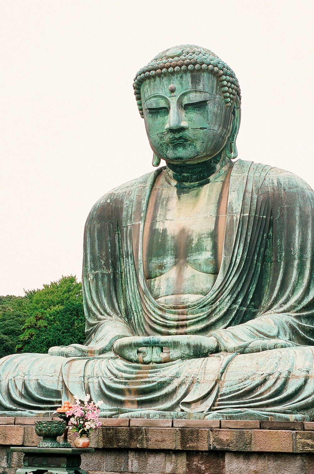 statue en béton gris près de l’herbe verte pendant la journée