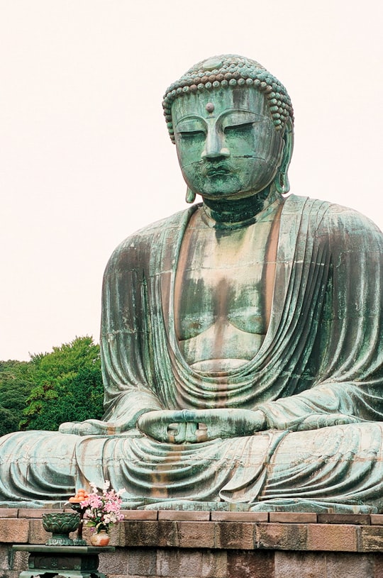 gray concrete statue near green grass during daytime in Kōtoku-in Japan