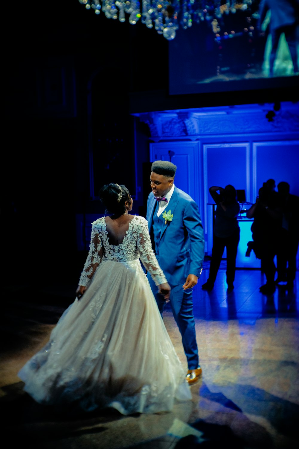 man in blue suit jacket and woman in white wedding dress walking on hallway