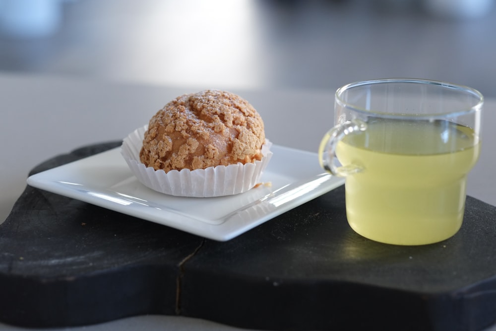 clear glass mug beside cupcake on white paper plate
