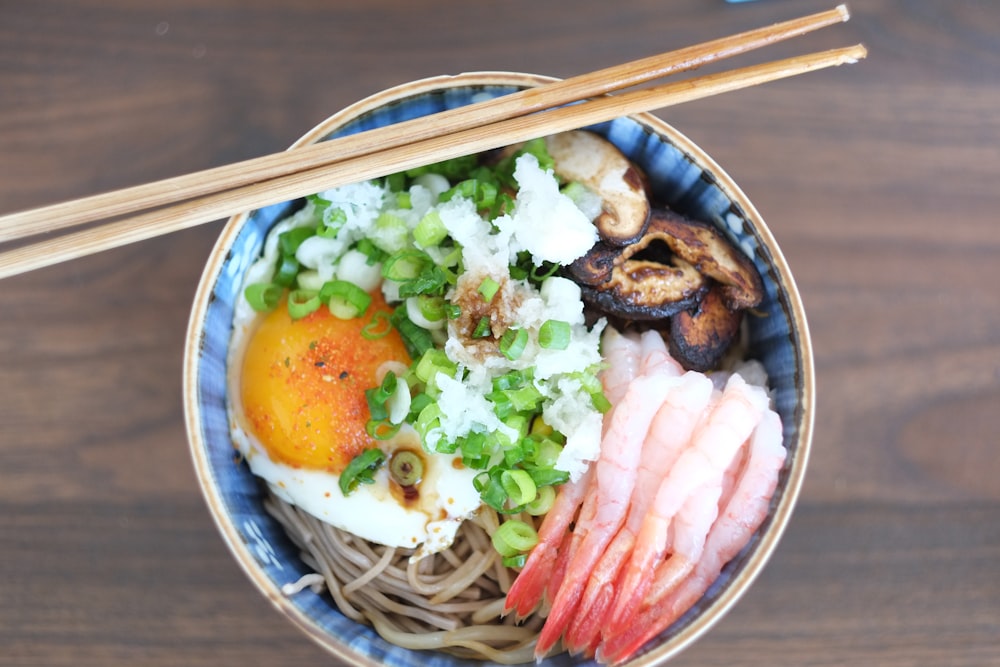 brown chopsticks on white and blue ceramic bowl