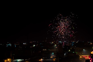 Colorful fireworks exploding in the night sky above a cityscape.