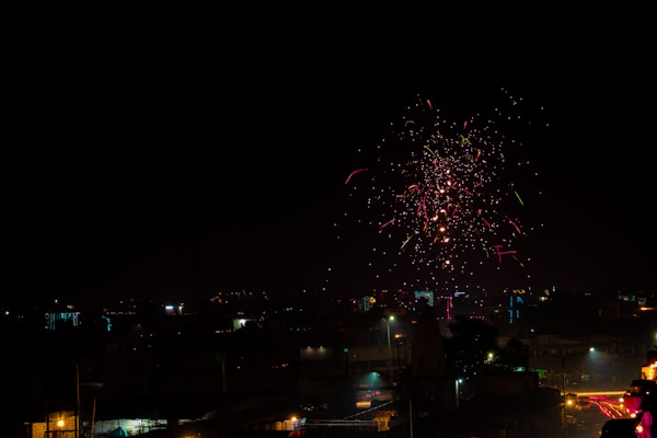 Colorful fireworks exploding in the night sky above a cityscape.