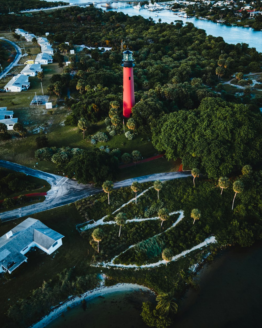 red and black lighthouse near green trees during daytime