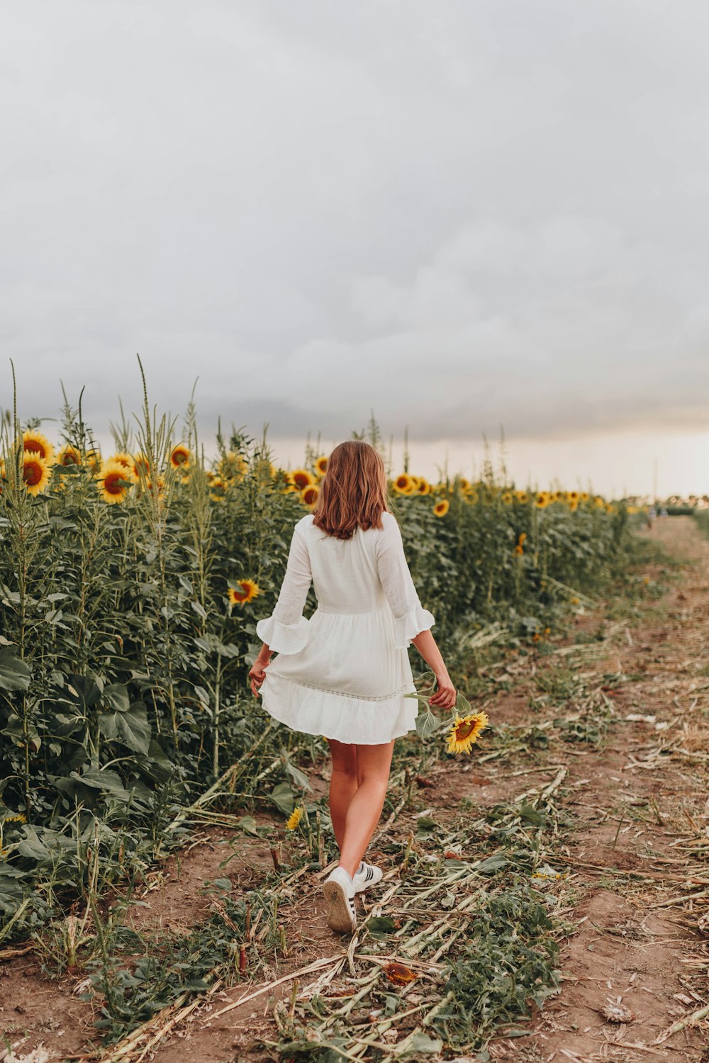 woman in white long sleeve dress standing on green grass field during daytime