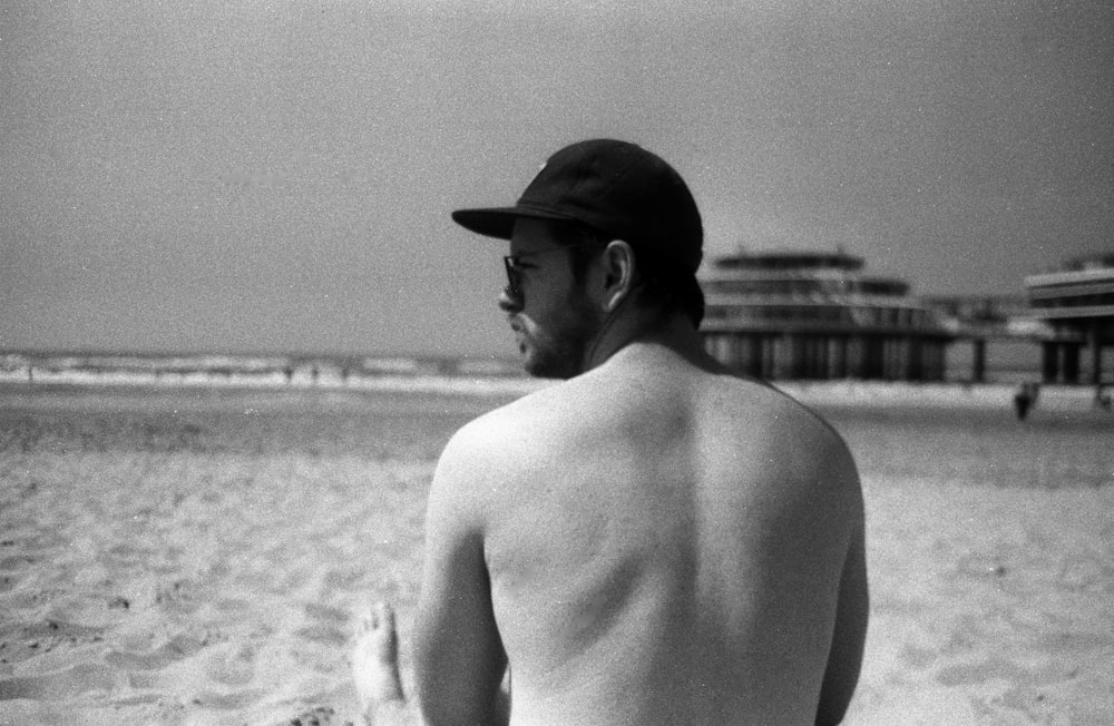 topless man wearing hat standing on beach